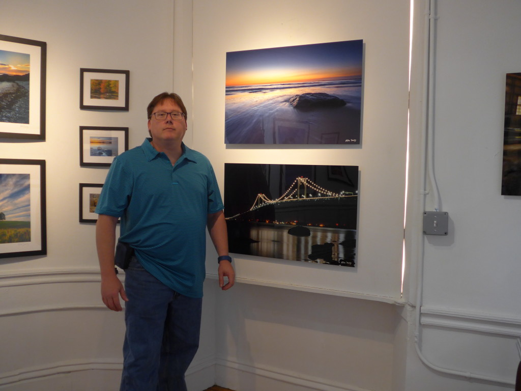 Photographer Mike Dooley stands with 2 of his 20"x30" aluminum prints at Peter Miller Fine Art Gallery