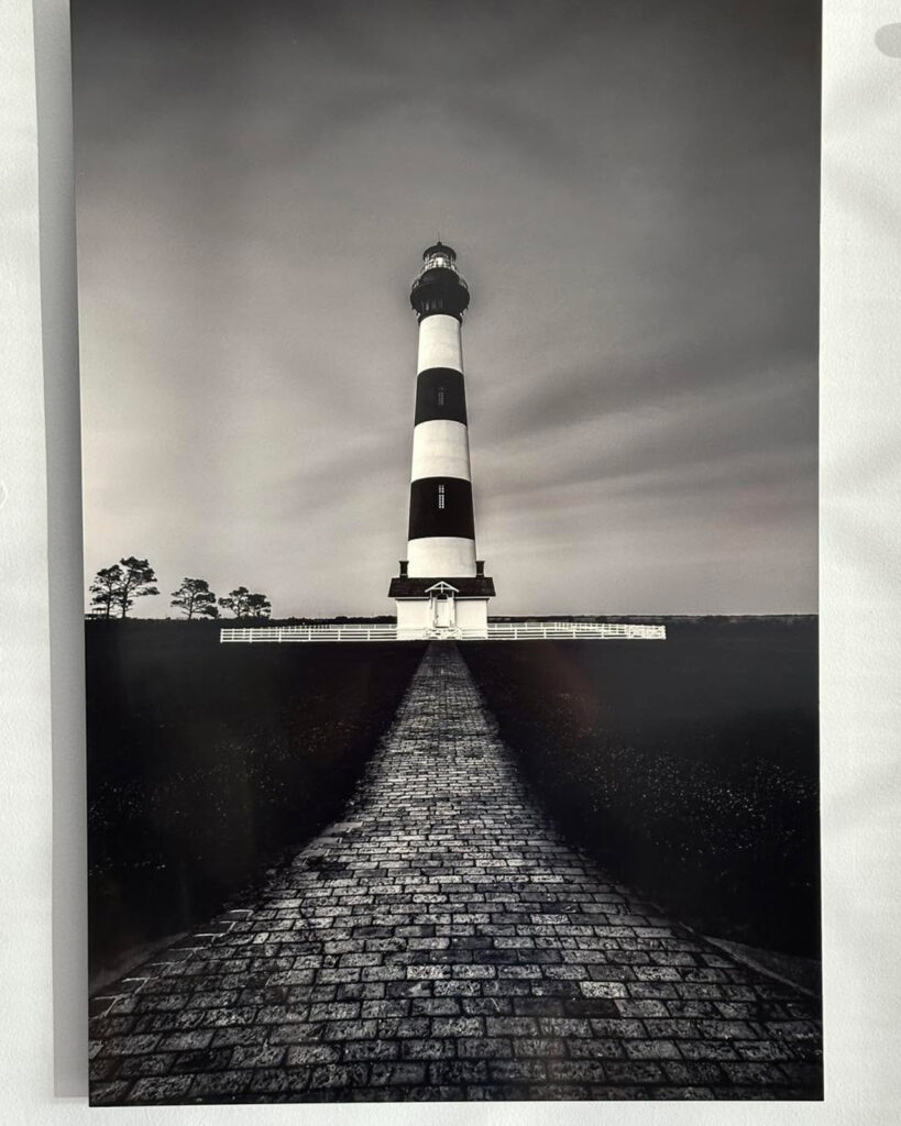 Mike Dooley’s 24x36" fine art metal print of Bodie Island Lighthouse displayed at a book signing event, showcasing vibrant coastal seascape photography.