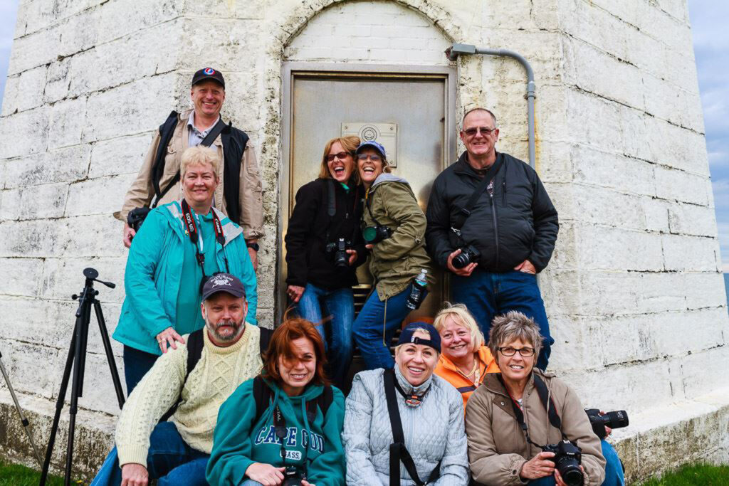 Group of photography workshop participants standing in front of Point Judith Lighthouse in Narragansett, Rhode Island, smiling after a seascape photography class with Mike Dooley Photography.