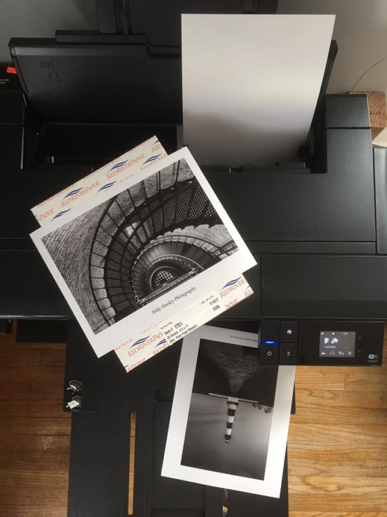 Epson printer with fine art photography prints displayed on top during printing process.