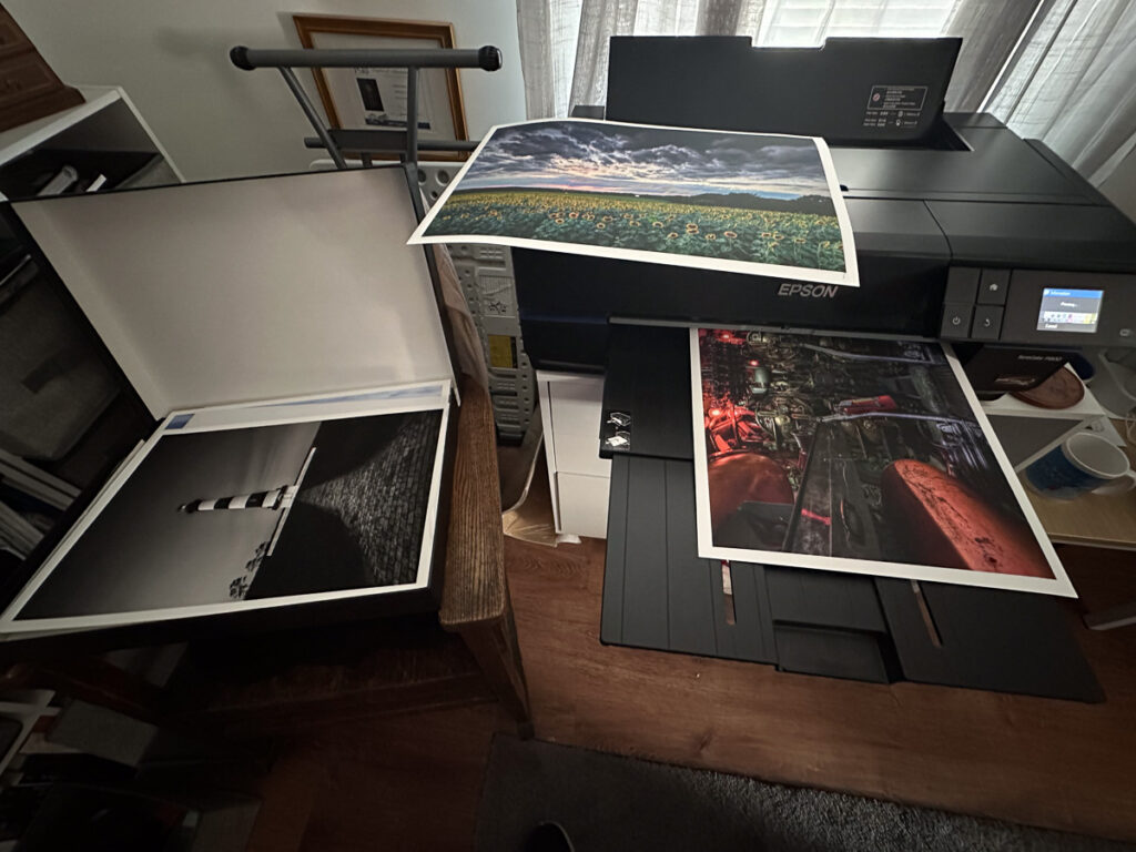 Multiple fine art photo prints emerging from the Epson SureColor P800 printer, freshly printed and ready to be handled
