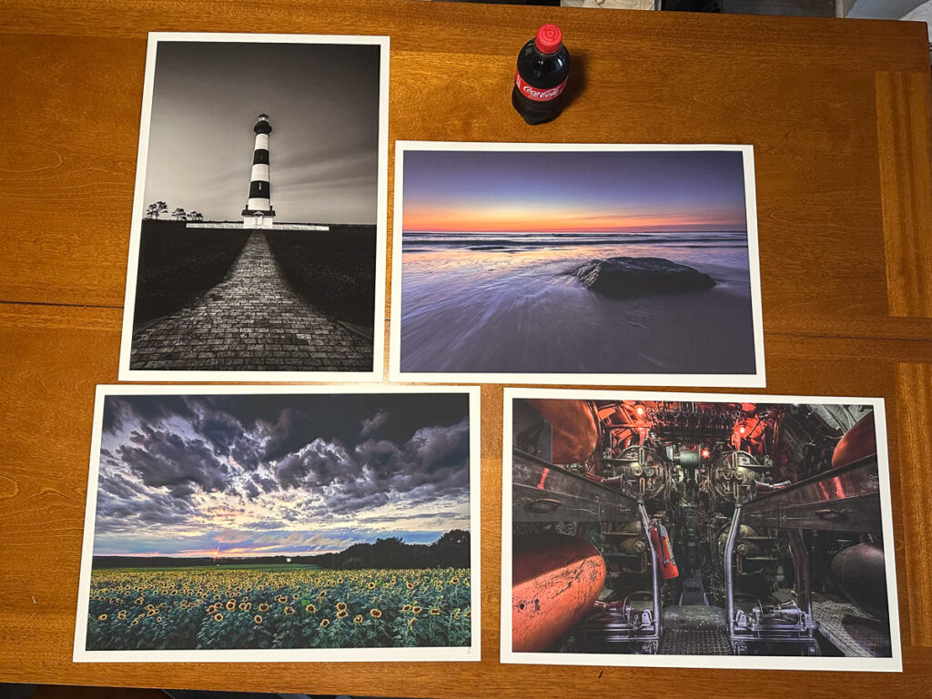Fine art landscape and seascape photography prints laid out on dining room table for review.