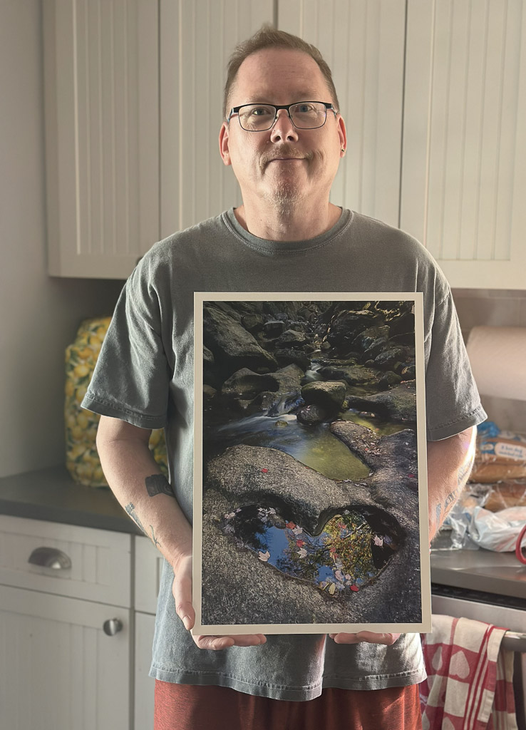 Mike Dooley holding a 13x19" metal print of “Love on the Rocks” on Epson Cold Press Bright paper