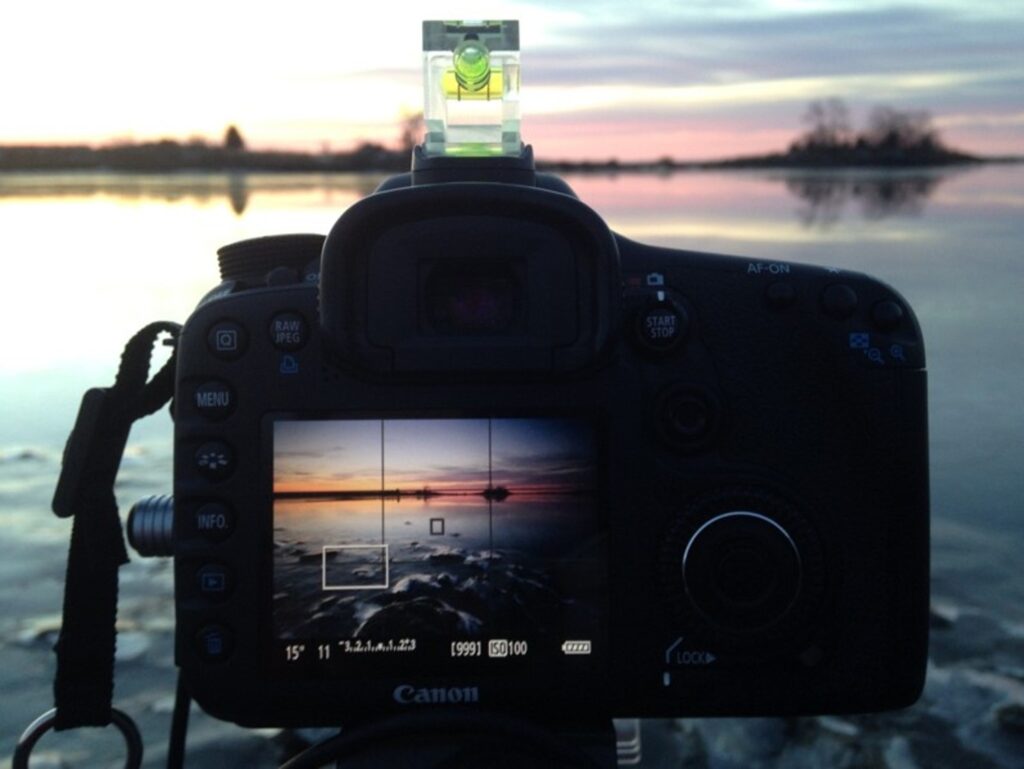 Behind the scenes photo of Mike Dooley setting up tripod and camera at Salter Grove, Warwick RI, preparing for a seascape shot.