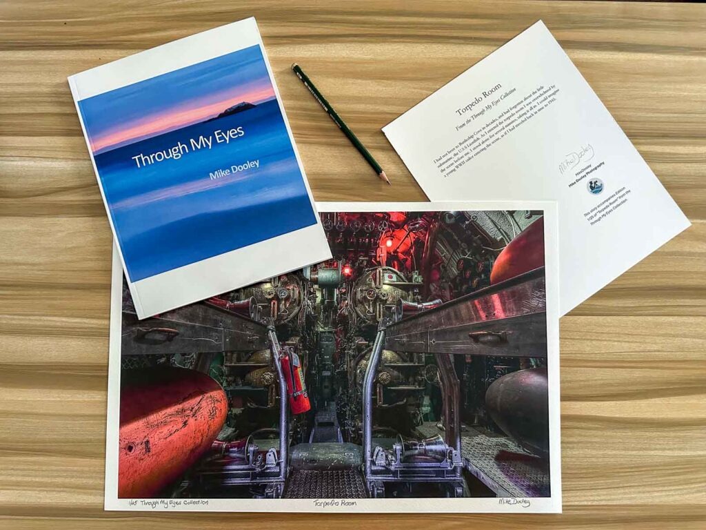 Photograph showing a signed, numbered 13x19 print of “Torpedo Rooms – Silence in Steel,” an 8.5x11 story card, and the book Through My Eyes by Mike; part of the Signature series
