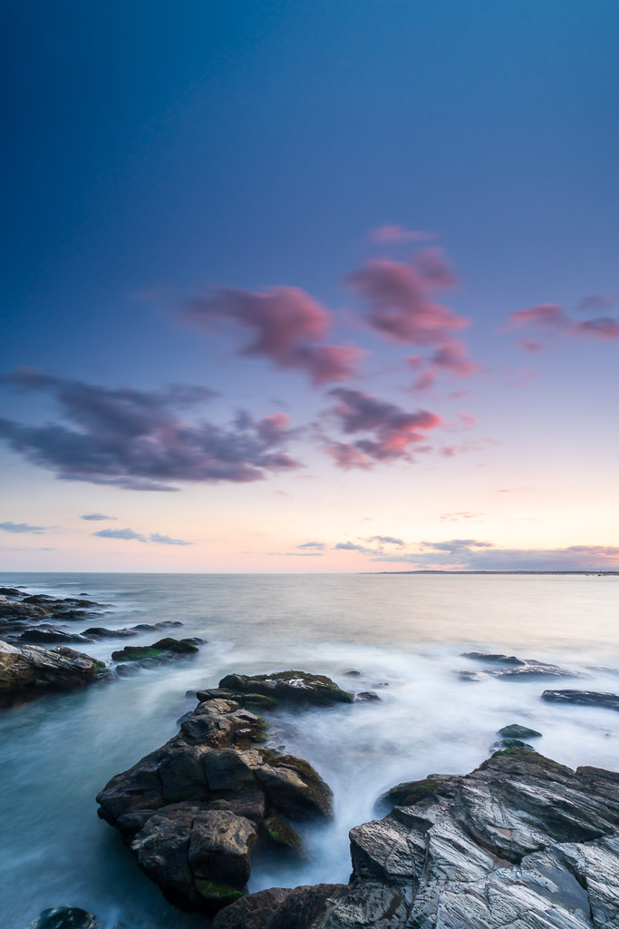 Rocky Newport coastline with pink clouds at sunset, photographed from the Cliff Walk in Rhode Island