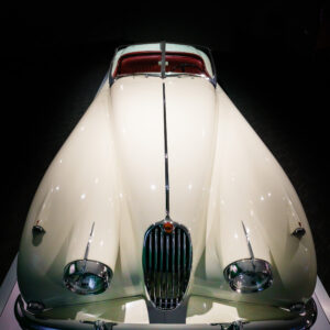 Side view of a 1956 Jaguar XK140 Roadster showing long hood and sweeping fenders at the Newport Car Museum, photographed as a fine art print by Mike Dooley.