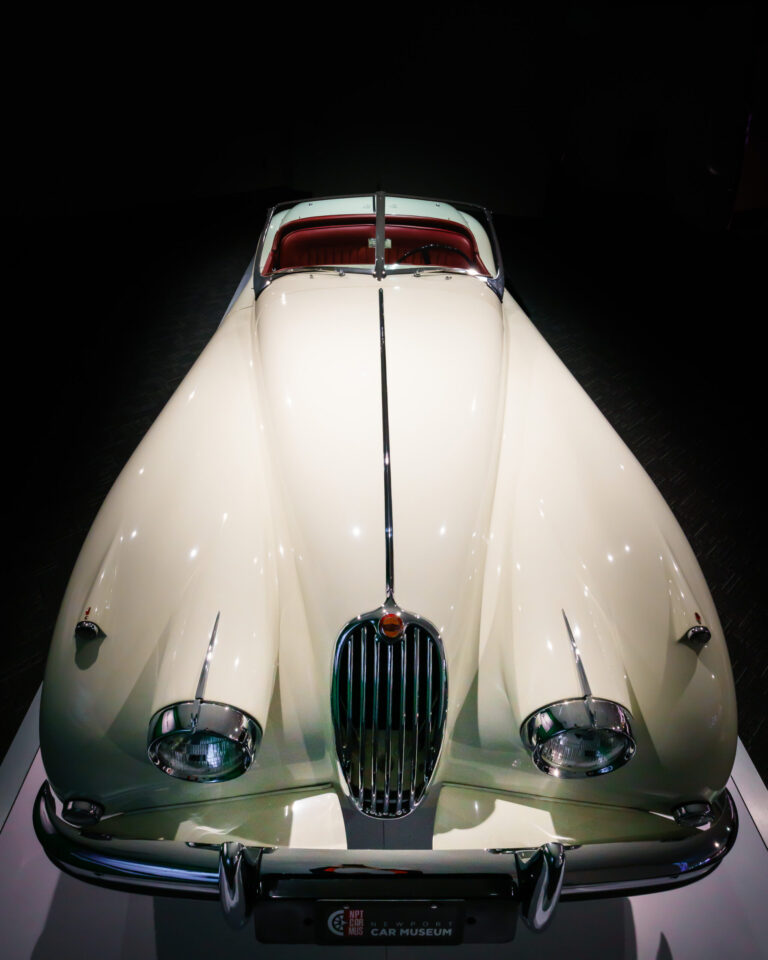 Side view of a 1956 Jaguar XK140 Roadster showing long hood and sweeping fenders at the Newport Car Museum