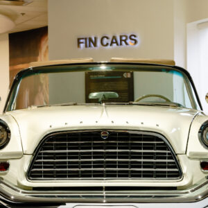 Chrome-covered hood of a vintage Chrysler at the entrance to the Fins exhibit at the Newport Car Museum, photographed as a fine art print by Mike Dooley.