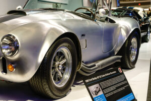 Side view of a bare aluminum Shelby Cobra at the Newport Car Museum