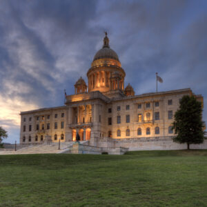 Rhode Island State House at dusk with warm lights glowing against a twilight sky in Providence.