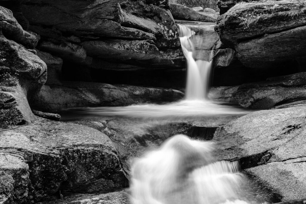 Black-and-white photograph of Sabaday Falls in Franconia Notch, New Hampshire, showcasing cascading water and natural texture.
