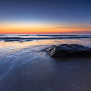 Sunrise over a quiet beach on Block Island, Rhode Island, captured just before the sun crosses the horizon, photographed by Mike Dooley.