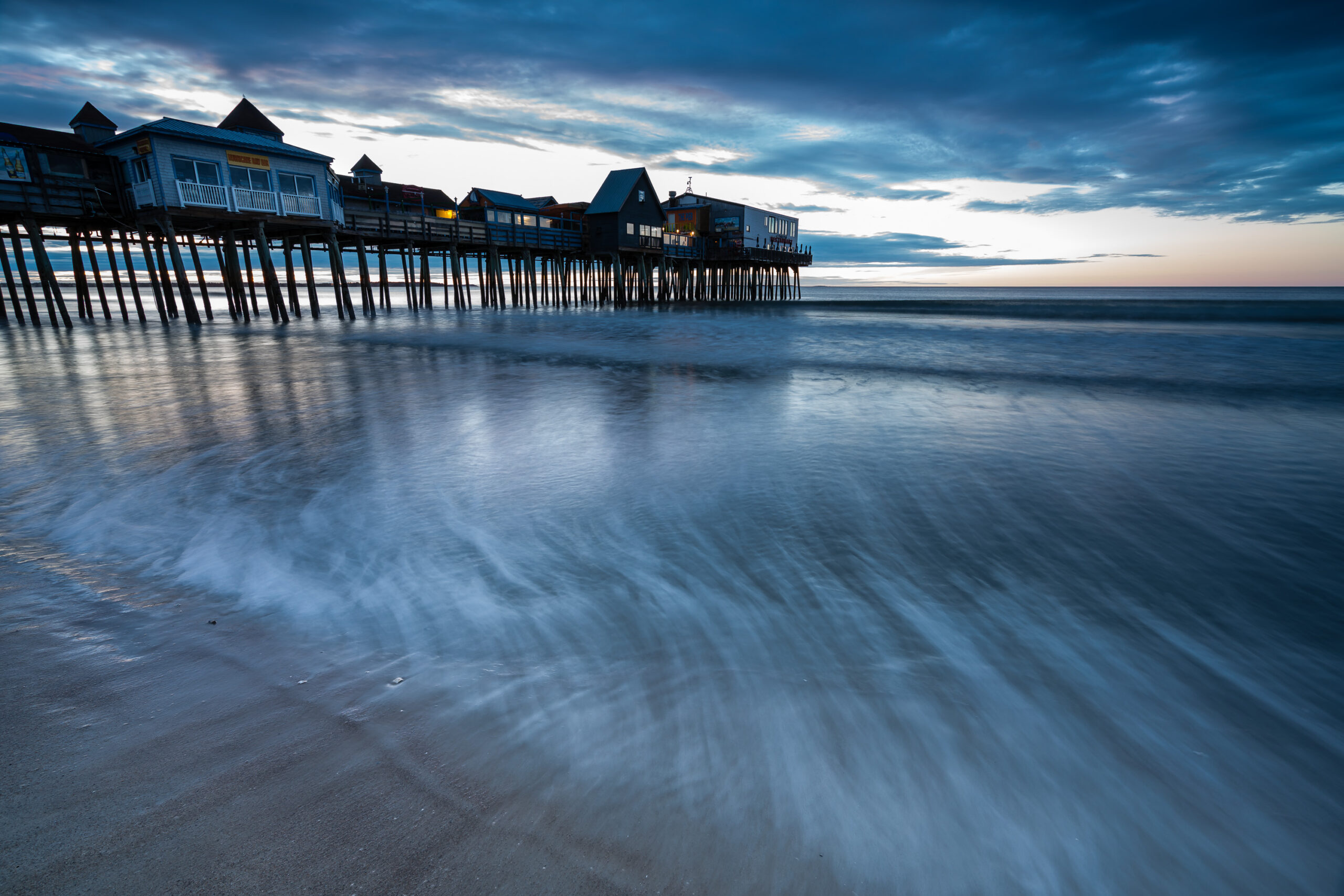Old Orchard Beach Pier at blue hour before sunrise, with soft early morning light over the water, photographed by Mike Dooley.
