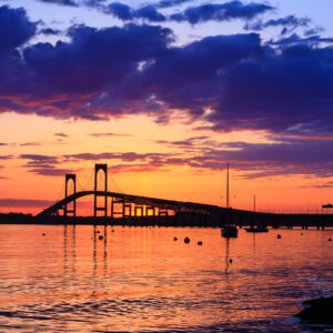 Sunset behind the Newport Bridge with dramatic clouds and warm lighting, photographed by Mike Dooley.