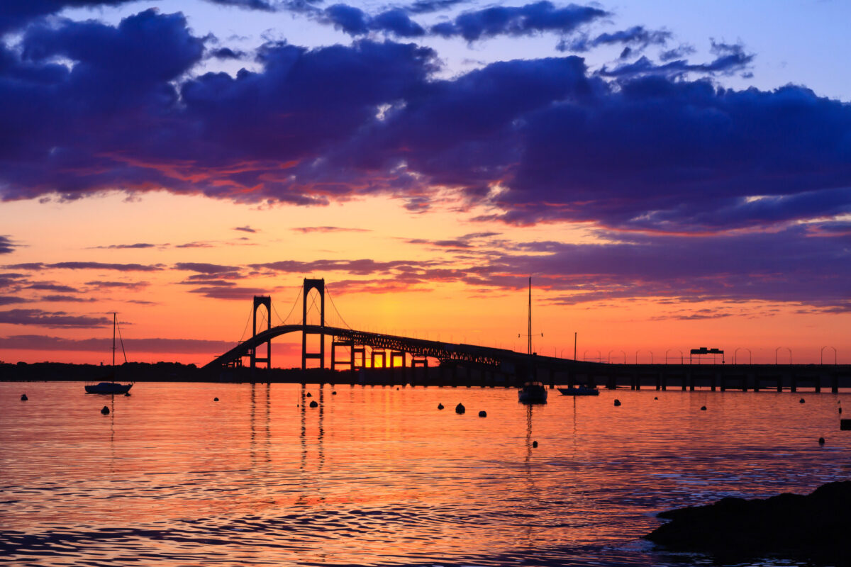 Sunset behind the Newport Bridge with dramatic clouds and warm lighting
