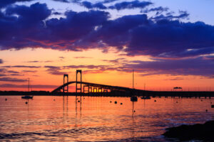 Sunset behind the Newport Bridge with dramatic clouds and warm lighting, photographed by Mike Dooley.