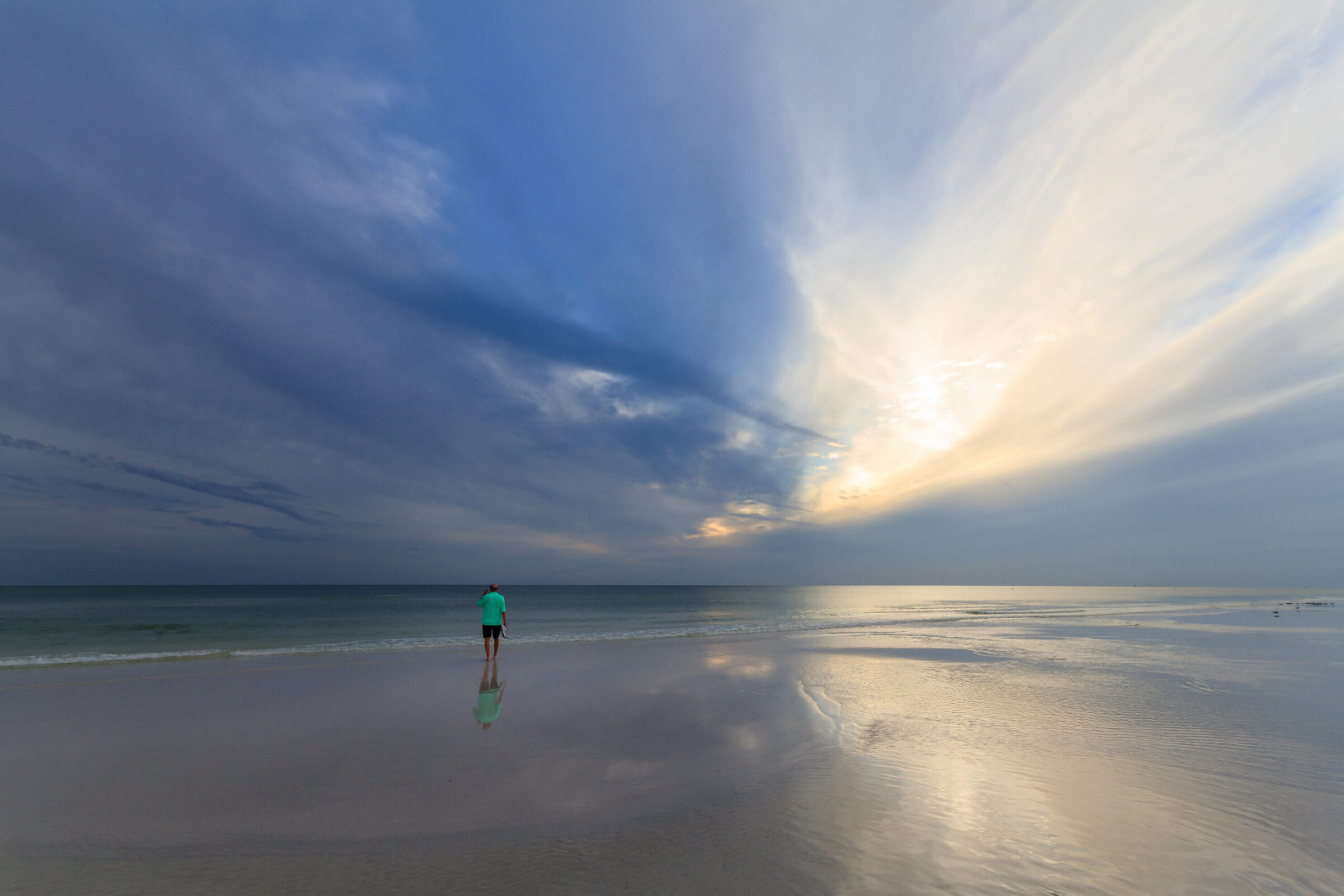 Mike Dooley's dad walking alone on Siesta Key beach at sunset, reflected in the wet sand
