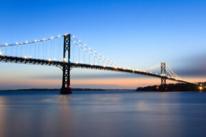 Mount Hope Bridge at dusk with calm waters and a blue evening sky, photographed by Mike Dooley.