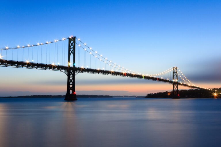 Mount Hope Bridge at dusk with calm waters and a blue evening sky, photographed by Mike Dooley.