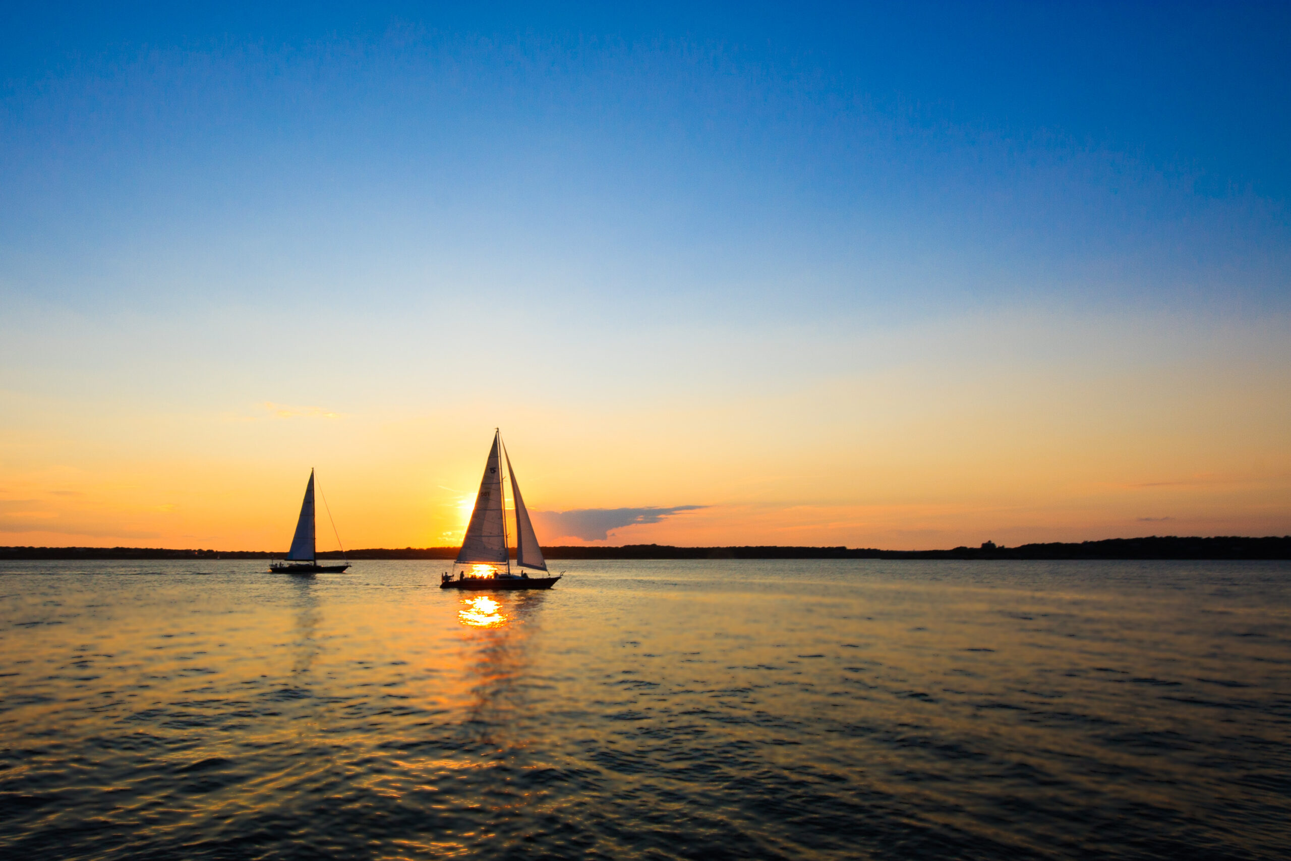 Sailboats sailing on Narragansett Bay at sunset in Newport, Rhode Island, photographed as a fine art print by Mike Dooley.