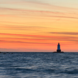 Sakonnet Point Lighthouse with dramatic, colorful clouds in the background, photographed by Mike Dooley.