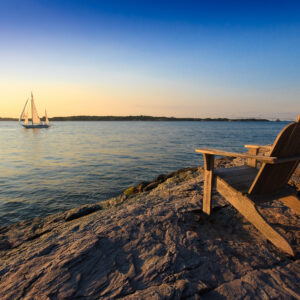 Sailboat sailing near the rocks by Castle Hill Lighthouse in Newport, Rhode Island, photographed as a fine art print by Mike Dooley.