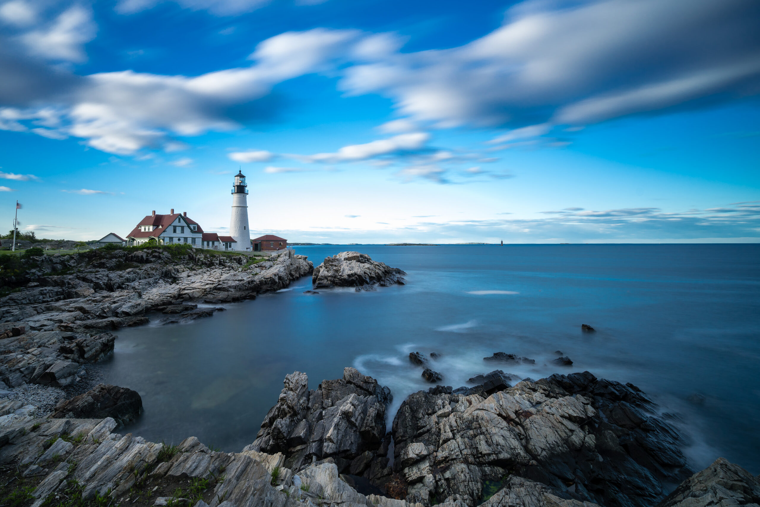Portland Head Lighthouse at sunset in Maine, photographed by Mike Dooley Photography, with warm light illuminating the coastline.