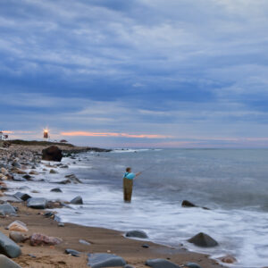 Fisherman casting a line in front of Point Judith Lighthouse, photographed as a fine art print by Mike Dooley.