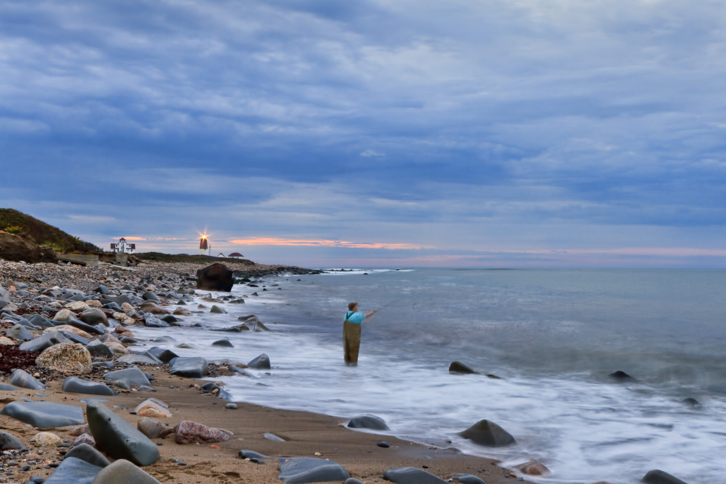 Fisherman casting a line in front of Point Judith Lighthouse