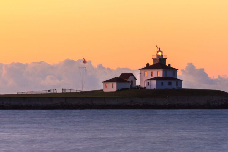Watch Hill Lighthouse at sunrise, seen through a long lens, with soft morning light, photographed by Mike Dooley.