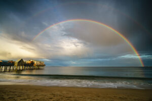 Double rainbow over Old Orchard Beach, Maine, stretching across the sky above the ocean and sandy shoreline.