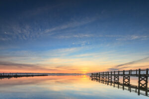 Pier extending into Naragansett Bay at sunrise, with golden light reflecting on the water