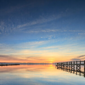 Pier extending into Naragansett Bay at sunrise, with golden light reflecting on the water