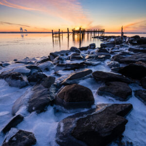 Winter sunrise at Rocky Point Park, Rhode Island, with ice-covered rocks along the shoreline
