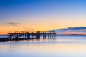 Long exposure photograph of Rocky Point Pier at dawn with smooth surf, captured by Mike Dooley.