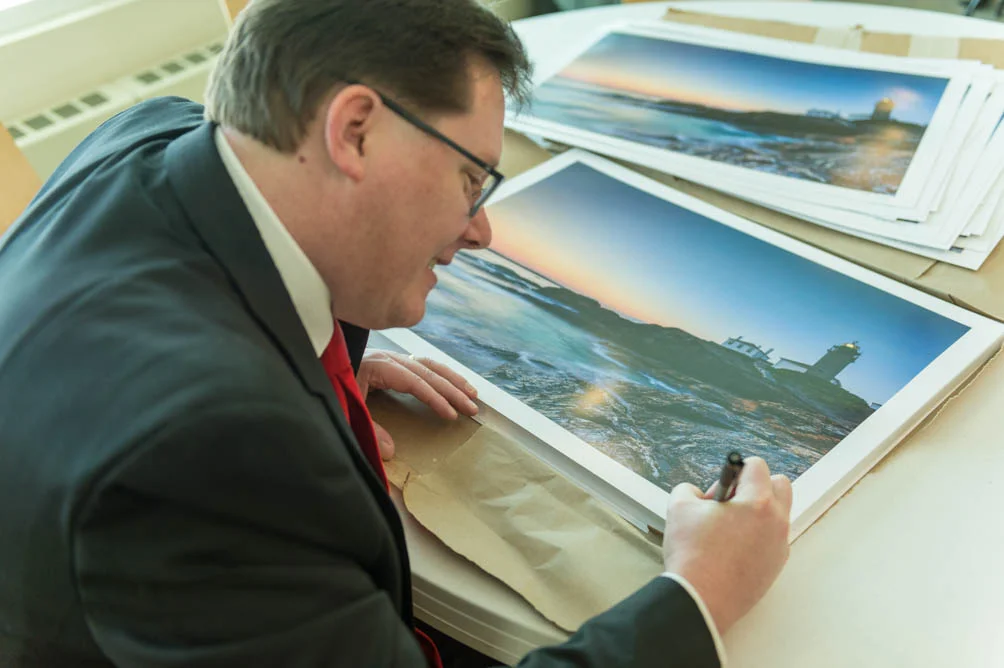 Mike signs a print of The Lighthouse at the 2015 RI Blood Center Seasons Pass press conference