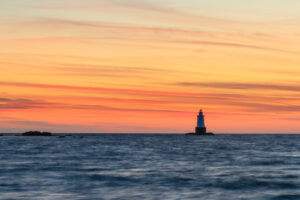 Sakonnet Point Lighthouse at sunset under streaks of orange cloud, Little Compton, Rhode Island