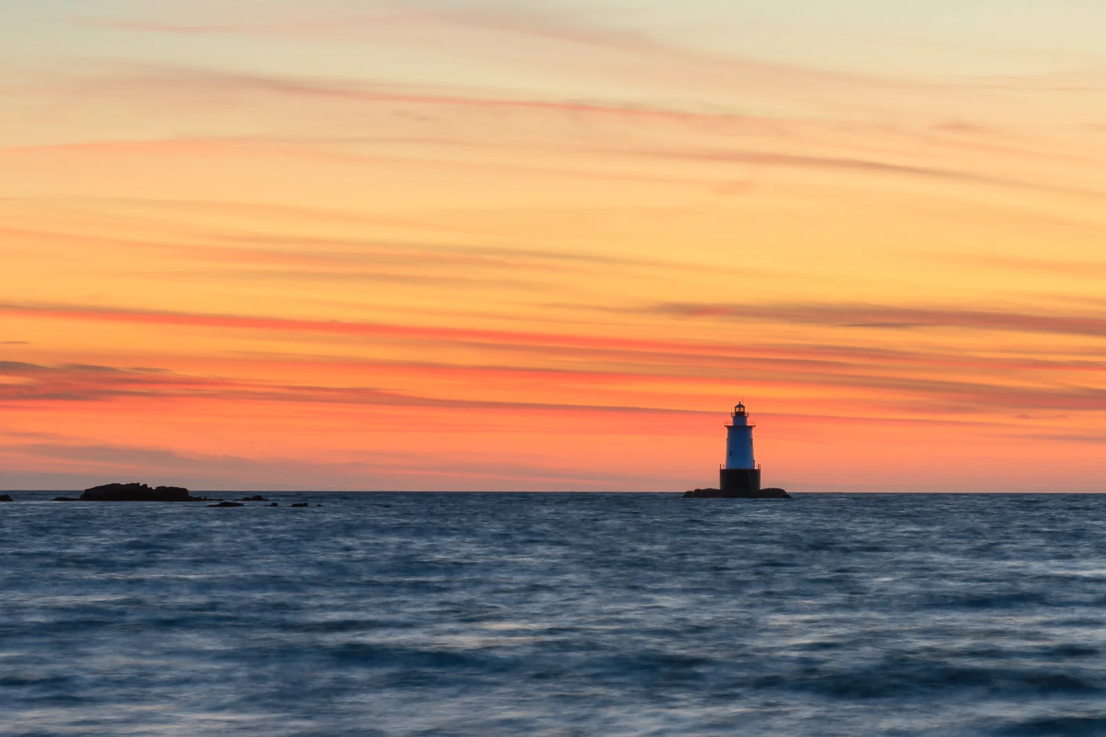 Sakonnet Point Lighthouse at sunset under streaks of orange cloud, Little Compton, Rhode Island