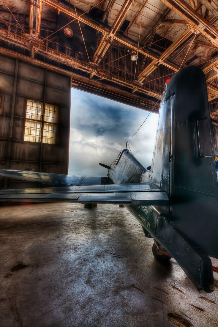 The F6F Hellcat fighter plane backlit in a hangar at the Quonset Air Museum