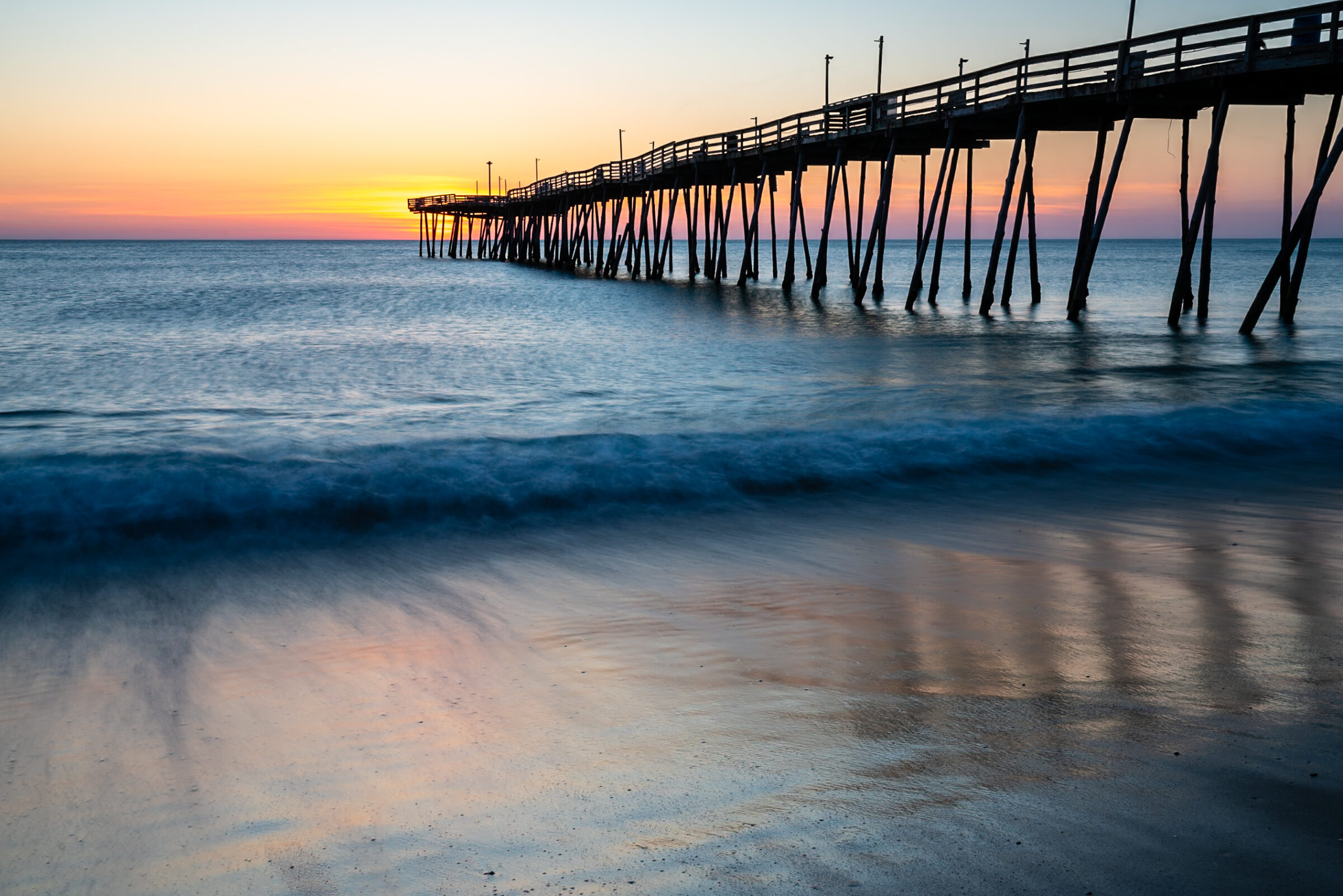 Sunrise glowing behind Avalon Pier and the surf, Outer Banks, North Carolina, fine art photograph by Mike Dooley