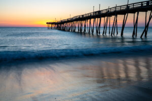Sunrise light on the surf rolling beneath a fishing pier on North Carolina's Outer Banks