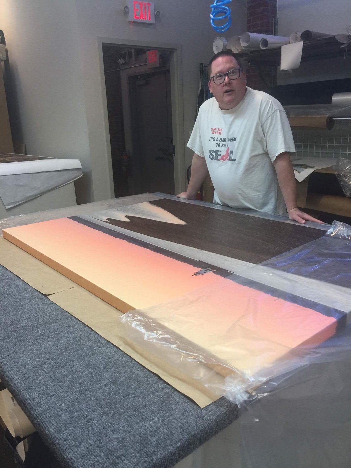Mike Dooley signing a large canvas print of Conimicut Lighthouse at a print shop in Warwick, Rhode Island.