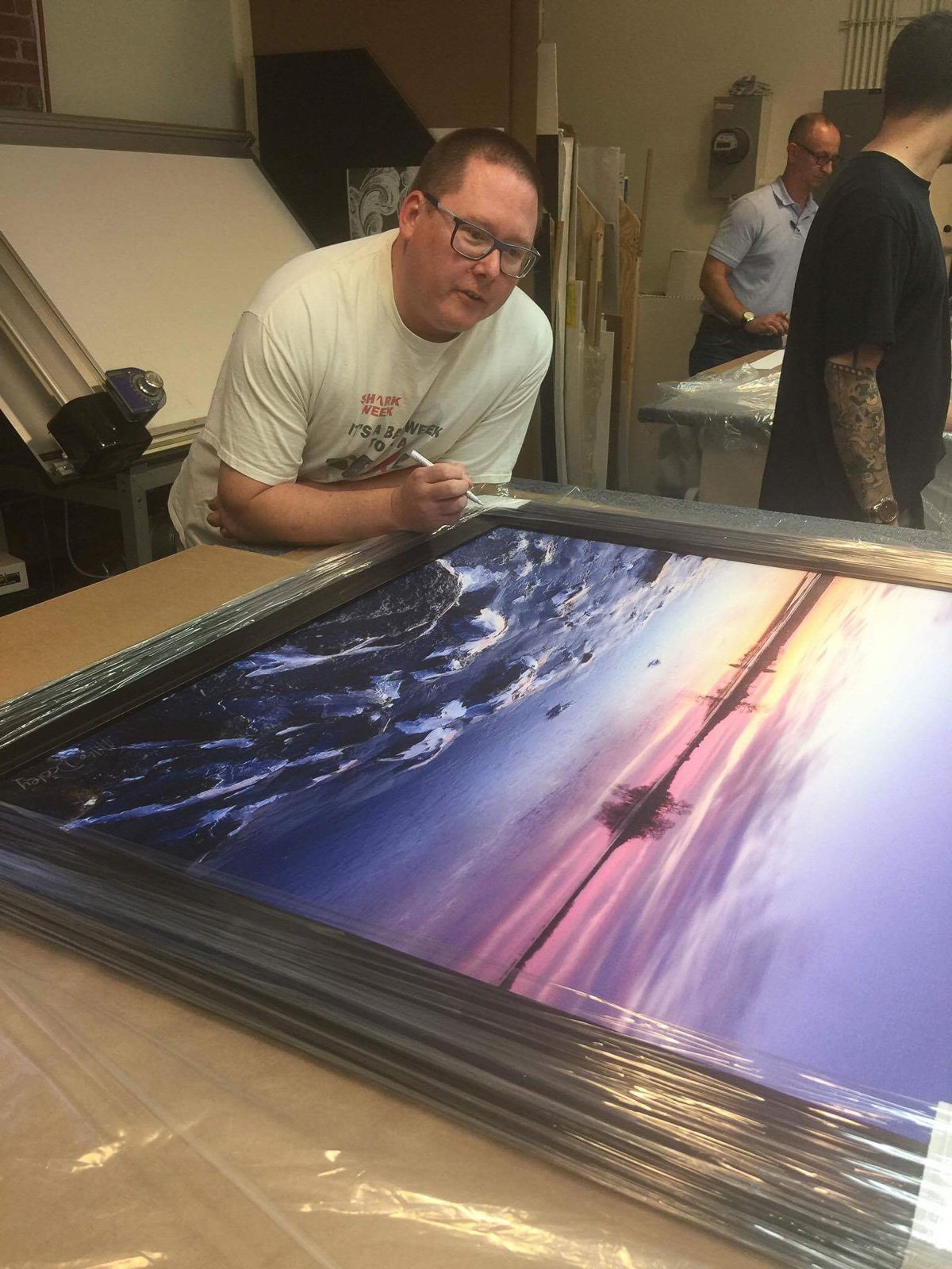 Mike Dooley signing a large framed winter print of Salter Grove in Warwick before installation at the Rhode Island Veterans Home.