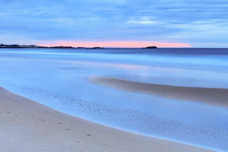 Curve of wet sand reflecting a blue sky with a pink band on the horizon at sunrise, Narragansett Beach, Rhode Island, by Mike Dooley