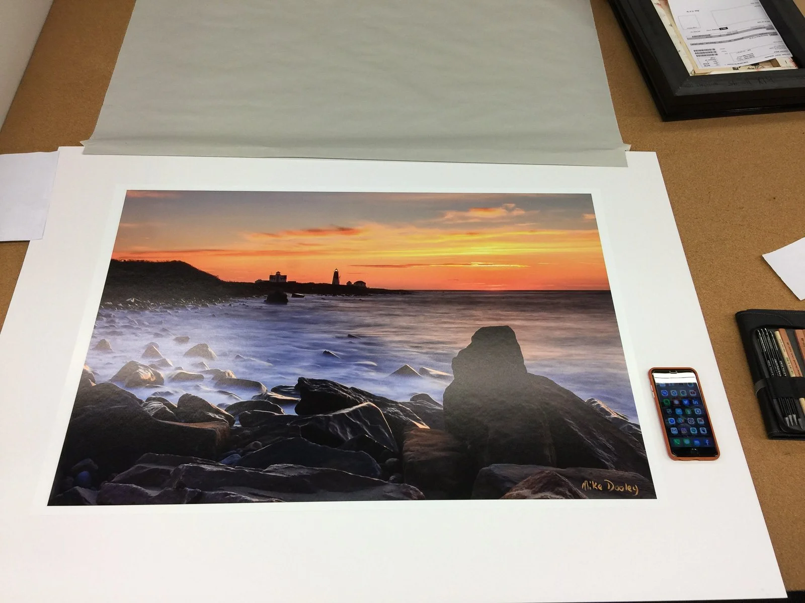 Large signed paper print of Point Judith Lighthouse by Mike Dooley on a framing table, ready to be framed for a local restaurant.