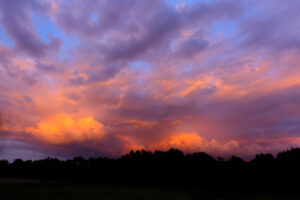 Purple and orange storm clouds at sunset over silhouetted trees, Rhode Island, fine art photograph by Mike Dooley