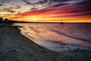 Red and orange sunset clouds over the bay with a boat offshore, Conimicut, Warwick, Rhode Island, by Mike Dooley