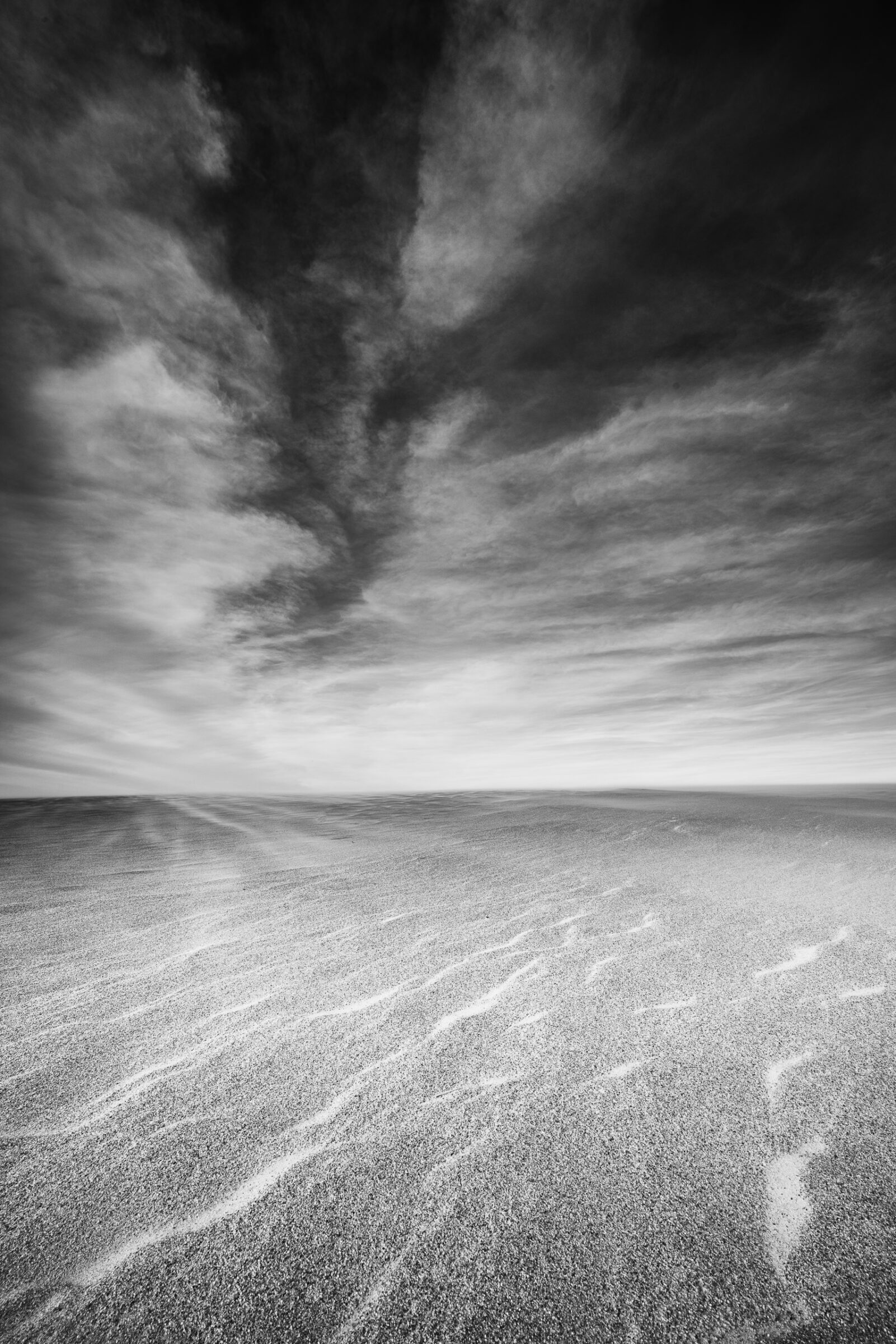 Wind-blown sand and stormy clouds over Jockey's Ridge State Park, Outer Banks, North Carolina, black and white photograph by Mike Dooley